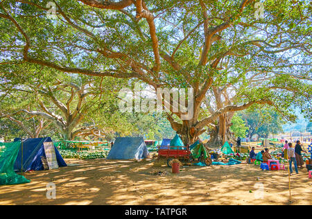 PINDAYA, MYANMAR - 19. FEBRUAR 2018: Die Stände der Wassermelone Markt sind unter der riesigen Bantambaumbäumen der lokalen Garten gelegen, im Februar Stockfoto