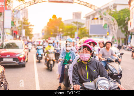 Da Nang, Vietnam - März 21, 2019: Zwei junge Leute, die sich für Schutzmasken auf einem Roller in Le Duan Street bei Sonnenuntergang. Stockfoto