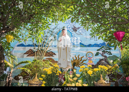 Da Nang, Vietnam - am 25. März, 2019: Lady Buddha (Quan bin, wie Guanyin in China bekannt) und buntes Mosaik unter den Blumen in Chua Tan Ninh buddhistischen Tempel Stockfoto