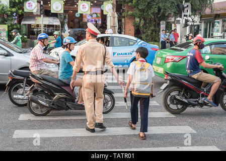 Da Nang, Vietnam - 21. März 2019: eine vietnamesische Verkehrspolizist nimmt ein Junge auf der stark befahrenen Straße. Stockfoto