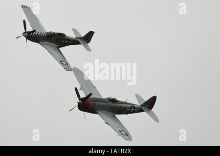 TF-51 D Mustang "Maria" und Republic P-47D Thunderbolt 'Nellie' fliegen in Formation während des Duxford Air Festival im Imperial War Museum Duxford, England, 26. Mai 2019. Einer der besten Kämpfer der Alliierten des Zweiten Weltkriegs, "Maria" in der gleichen schwarzen und weißen Schachbrett-Fliesen wie Markierungen benennenden U.S. Army Air Forces Mustangs in der Royal Air Force Duxford 1944 stationiert gemalt wird. (U.S. Air Force Foto von Master Sgt. Eric Burks) Stockfoto