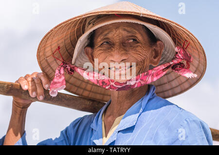 Hoi An, Vietnam - Oktober 28, 2018: ein lächelndes ältere Vietnamesische Dame, ein Straßenhändler, stellt in einem konischen Hut. Stockfoto