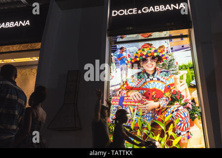 Ho Chi Minh City, Vietnam - 23. April 2019: Dolce&Gabbana shop Exterieur mit Passanten in der Nacht Straße, auf einem Motorrad und zu Fuß. Stockfoto