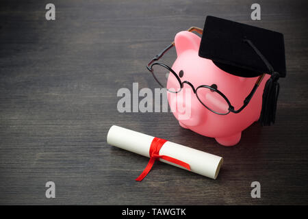 Piggy Bank mit einem Grad Gap und Diplom auf Holztisch, Stipendium Stockfoto