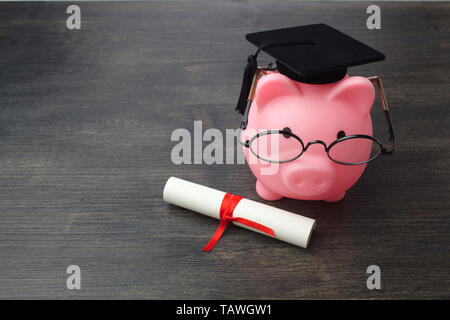 Piggy Bank mit einem Grad Gap und Diplom auf Holztisch, Stipendium Stockfoto