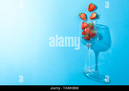 Wein Glas mit Erdbeeren auf farbigen Hintergrund, Platz für Text. Sommer süße Früchte und Beeren Stockfoto