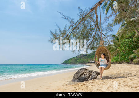 Happy Traveler asiatische Frau entspannend auf Luxus schwingen und suchen schöne Natur Landschaft Strand. Sommer Urlaub Ferien reisen reise Konzept Stockfoto