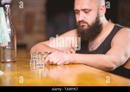 Hipster brutalen Mann, Alkohol zu trinken bestellen mehr Getränke an der Theke. Alkoholismus und Depression. Kerl verbringen Freizeit in bar mit Alkohol. Mann betrunken sitzen alleine in eine Kneipe. Alkohol Konzept süchtig. Stockfoto