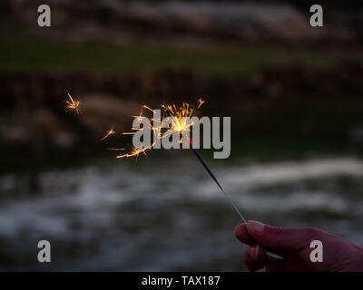 Eine nicht erkennbare Person mit einer Wunderkerze sizzling in seiner Hand. Stockfoto