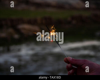 Eine nicht erkennbare Person mit einer Wunderkerze sizzling in seiner Hand. Stockfoto