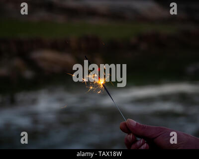 Eine nicht erkennbare Person mit einer Wunderkerze sizzling in seiner Hand. Stockfoto