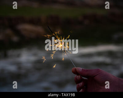 Eine nicht erkennbare Person mit einer Wunderkerze sizzling in seiner Hand. Stockfoto