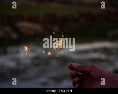 Eine nicht erkennbare Person mit einer Wunderkerze sizzling in seiner Hand. Stockfoto