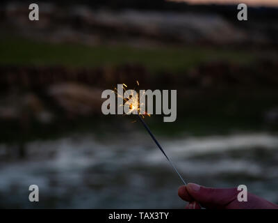 Eine nicht erkennbare Person mit einer Wunderkerze sizzling in seiner Hand. Stockfoto