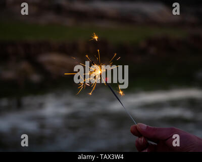 Eine nicht erkennbare Person mit einer Wunderkerze sizzling in seiner Hand. Stockfoto