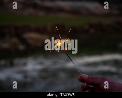 Eine nicht erkennbare Person mit einer Wunderkerze sizzling in seiner Hand. Stockfoto