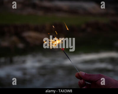 Eine nicht erkennbare Person mit einer Wunderkerze sizzling in seiner Hand. Stockfoto
