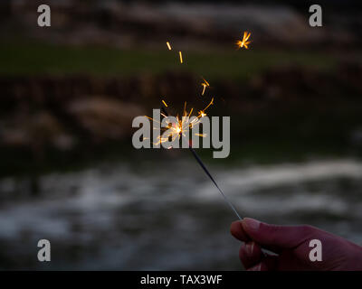 Eine nicht erkennbare Person mit einer Wunderkerze sizzling in seiner Hand. Stockfoto