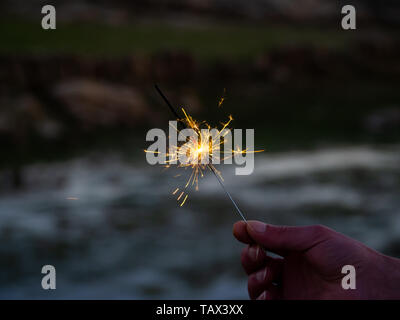 Eine nicht erkennbare Person mit einer Wunderkerze sizzling in seiner Hand. Stockfoto