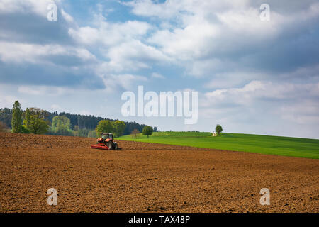 Bayerische Landschaft mit Traktor pflügt das Feld bereitet den Boden für die Aussaat im Frühling Stockfoto