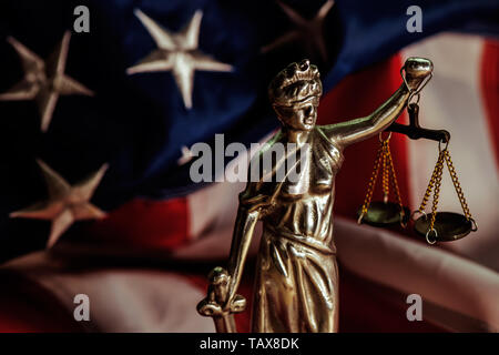 Recht und Gerechtigkeit in den Vereinigten Staaten von Amerika, Statue von Lady Gerechtigkeit mit USA-Flagge im Hintergrund, selektiver Fokus Stockfoto