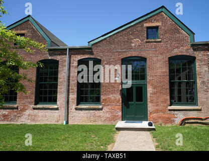 Fassade eines alten Seide Mühle. Die Fassade aus rotem Backstein, industrielle Türen und alten grünen Türen. Stockfoto