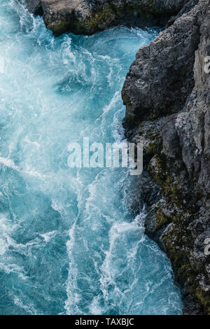 Das Eis blauen Wasser des Flusses Hvítá über den Wasserfall der Barnafoss in West Island, zwischen Klippen der schwarzen Lava gießen Stockfoto