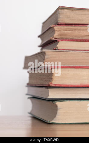 Stapel der alten staubigen Bücher auf einer hölzernen Oberfläche Stockfoto