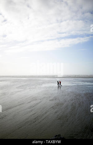 Paar ein Spaziergang am Strand entlang braving stürmischen Bedingungen mit Gail force Winds Stockfoto