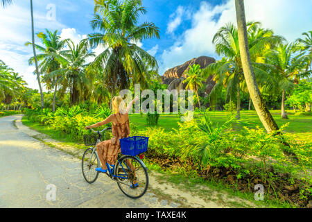 La Digue, Seychellen. Touristische Frau auf Fahrrad wies Riese Union Rock, ein Monolith in der Union Estate ein ehemaliger Kokos und Vanille Plantage in der Nähe von Anse Stockfoto