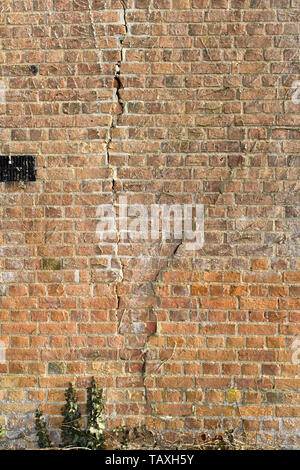 Risse in einem Alten roten Ziegelmauer aufgrund von Bodensenkungen Stockfoto