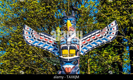 Eine Krähe saß auf dem bunten oben an der Kakaso 'Las Totempfahl" im Stanley Park. Die Oberseite ist ein Adler und ein Meer tragen ein Killer Whale. Stockfoto