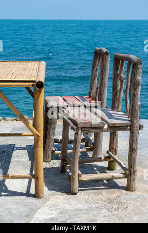 Bambus Tisch und Stühle aus Holz in leeren Cafe neben Meer Wasser in tropischen Strand. Close Up. Insel Koh Phangan, Thailand Stockfoto