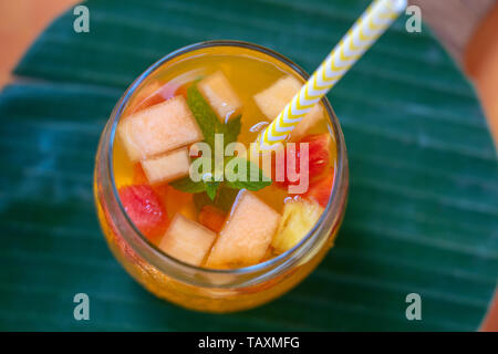 Frucht Limonade aus roten Erdbeeren, Melonen und Ananas in ein Glas. Close Up. Erfrischendes Getränk von Stück Obst Stockfoto