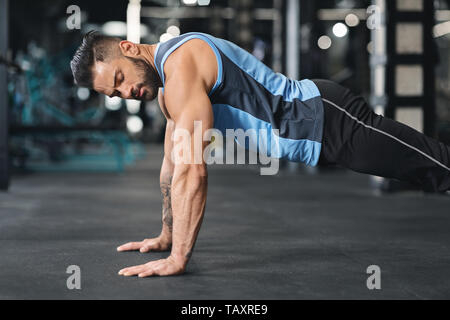 Sportlicher junger Mann pushups Tun in der Turnhalle Stockfoto
