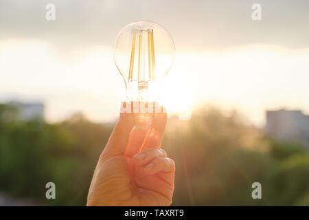 Glühlampen LED-Glühbirnen, Hand, Lampe, abend sonnenuntergang himmel Hintergrund. Stockfoto