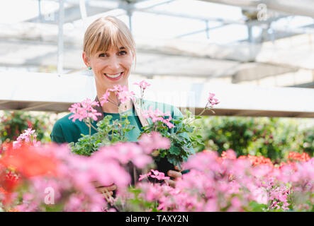 Gärtner Frau in Ihrem Gewächshaus mit Blumen für den Verkauf Stockfoto