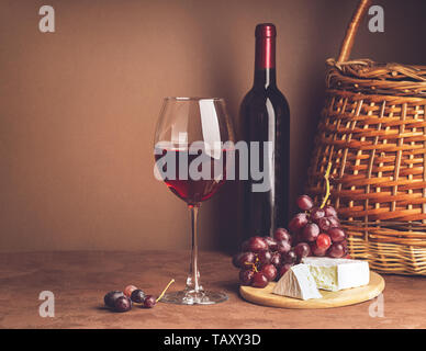 Ein Glas Wein, ein Bündel von roten Trauben Käse Schicht dunklen Hintergrund. Kopieren Sie Platz. Still life style Dunkel. Selektive konzentrieren. Stockfoto