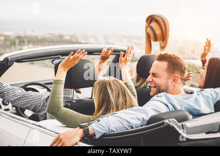 Gruppe von Freunden Spaß im Cabrio während der Fahrt bei Sonnenuntergang - Young Travel Menschen fahren ein Cabrio während der Sommerferien Stockfoto