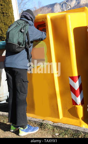 Der arme Junge mit einem Rucksack in den gelben Müll auf der Suche nach etwas zu recyceln in der Lage sein, es zu verkaufen. Stockfoto