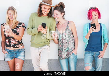 Gerne Freunde gerade auf Ihre Smart Handys Outdoor - Junge Generation Spaß mit neuer Technologie und soziales Netzwerk Stockfoto
