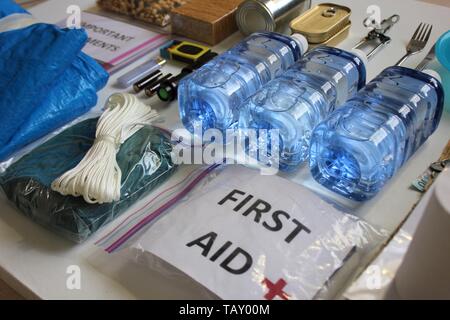 Im Voraus für eine Naturkatastrophe vorzubereiten durch die Zusammenstellung wichtiger Elemente, die Ihnen helfen, zu überleben. Wasser, Nahrung, Obdach, Lichtquelle, Erste Hilfe Kit. Stockfoto