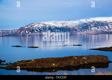 Isländische Fjord im Wasser mit Steinen im Vordergrund im besten Wetter wider Stockfoto