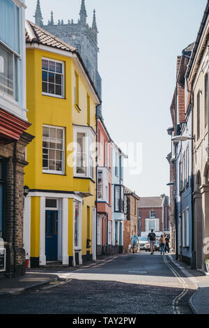 Cromer, Großbritannien - 20 April, 2019: Menschen zu Fuß vorbei an bunten Häuser in Cromer, einer Stadt am Meer in Norfolk und ein beliebter Ort für Familien, in Großbritannien. Stockfoto
