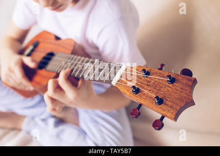 Hände Mädchen spielen der Gitarre. Ein Kind lernt Gitarre spielen. Selektive konzentrieren. Close-up. Das Konzept von Musik und Kunst Stockfoto