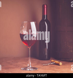 Ein Glas Rotwein und eine Flasche auf dunklem Hintergrund. Kopieren Sie Platz. Still life style Dunkel. Selektive konzentrieren. Stockfoto