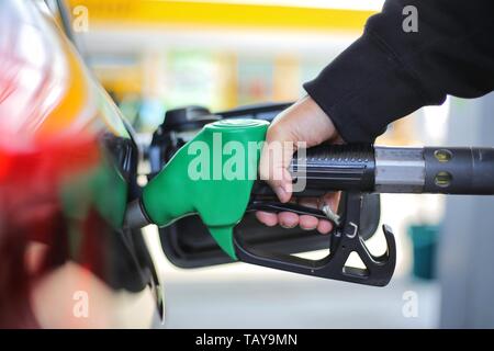 Nahaufnahme der Hand grün Benzin Düse und Gas Tank füllen von schwarzen Auto in Tankstelle Konzept der globalen Verbrauch fossiler Brennstoffe. Stockfoto