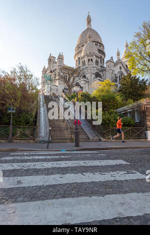 Paris, Frankreich, 12. April 2019: Ein Jogger auf der Straße läuft vor der Basilika von Sacré-coeur auf dem Hügel Montmartre an einem sonnigen Tag Stockfoto