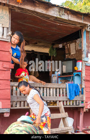 Mekong, Laos, Feb 2016: laotische Familie sucht über den Zaun und Entladen die Dinge aus ihrer schwimmenden Schiff Haus. Stockfoto