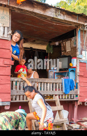 Mekong, Laos, Feb 2016: laotische Familie sucht über den Zaun und Entladen die Dinge aus ihrer schwimmenden Schiff Haus. Stockfoto